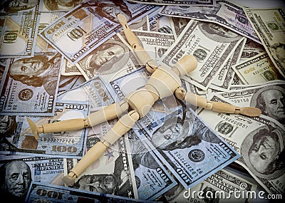 Doll made of wood lying on a lot of banknotes of dollar Americans Stock Photo