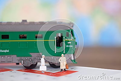 A doll model preparing to board the train next to the green leather train model Stock Photo