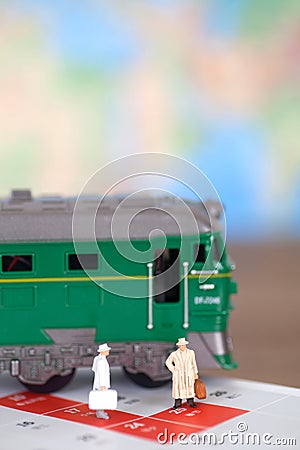 A doll model preparing to board the train next to the green leather train model Stock Photo