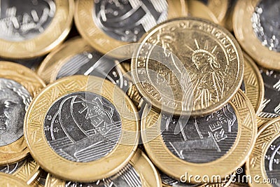 1 dollar coins in the middle of several 1 real coins on a wooden Stock Photo