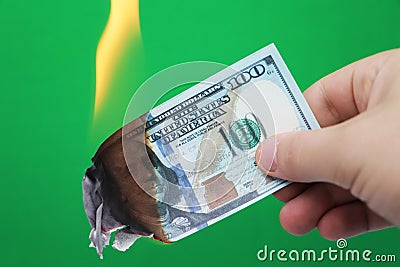 100 dollars burning on a green background. Concept of downturn in economy and loss Stock Photo