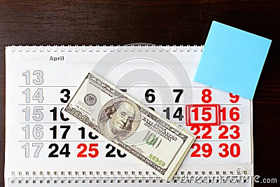 Dollars money and April 15 on calendar, empty sheet of paper Stock Photo