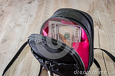 Dollars in an open backpack on a wooden background Stock Photo