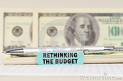 On the dollars are a pen and a sign with the inscription - Rethinking the budget Stock Photo