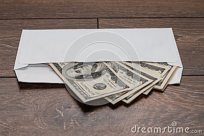 Dollars in a white envelope on a wooden background. Bribery concept. Salary in envelopes. Stock Photo