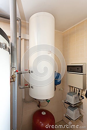 A domestic household boiler room with a new modern solid fuel boiler , heating electric warm water system and pipes. Stock Photo