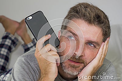 Domestic lifestyle portrait of young thoughtful and attractive man lying on bed at home thinking and daydreaming relaxed using Stock Photo