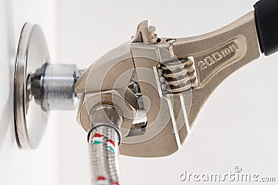 Domestic plumbing connections hoses. Using an adjustable wrench. Stock Photo