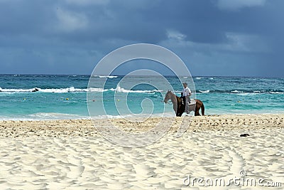 Dominican policeman on a black horse patrols the beach area. Editorial Stock Photo