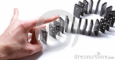 Dominoe pieces pushed by a human hand Stock Photo