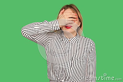 Don`t want to look at this! Portrait of shy confused girl with red lips in striped blouse covering eyes with hand Stock Photo