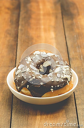 Donat in chocolate glaze is strewed with almonds. Wooden background Stock Photo