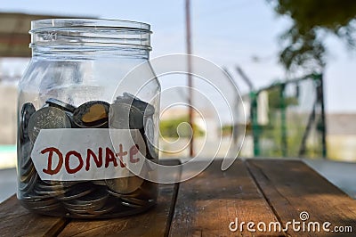 donate written label in jar and money,charity box in coins written text donate,donate written text on wooden table Stock Photo