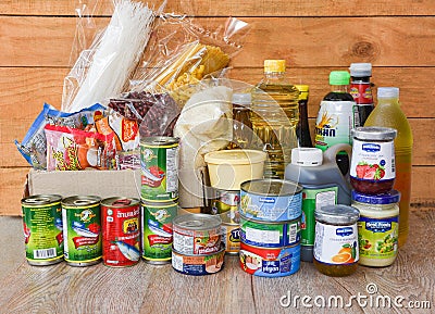 Donations box with canned food on wooden table background / pasta canned goods and dry food non perishable with oil rice noodles Editorial Stock Photo