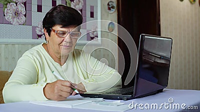 Donna anziana senior in occhiali che controlla i costi delle spese quotidiane sul computer portatile a casa archivi video Donna anziana senior in occhiali che controlla i costi delle spese quotidiane sul computer portatile a casa archivi video
