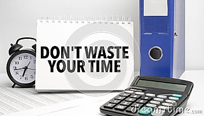 dont waste your time words on white notebook and calculator, black vintage alarm clock and blue paper folder Stock Photo
