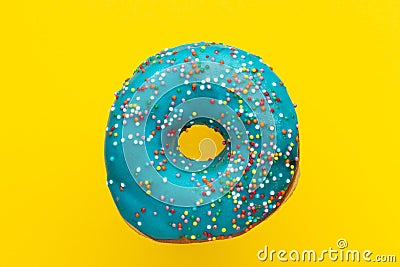 Donut blue with sprinkles on yellow background, close-up Stock Photo