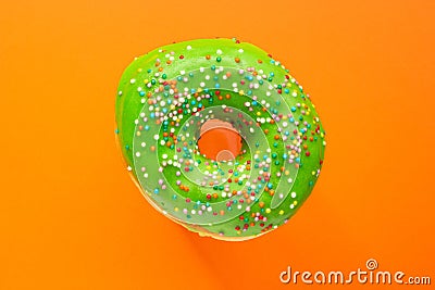 Donut green with sprinkles isolated on orange background, close-up Stock Photo