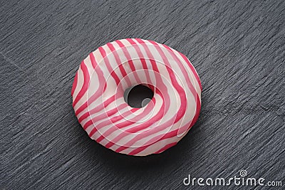 Donut with pink and white strips on black slate background Stock Photo