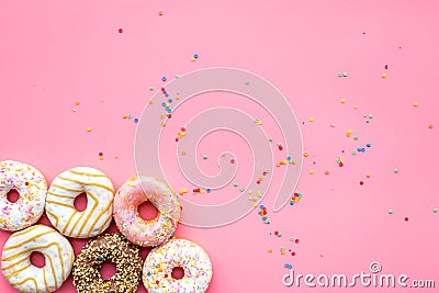 Donuts decorated icing and sprinkles on pink background top view copy space pattern Stock Photo