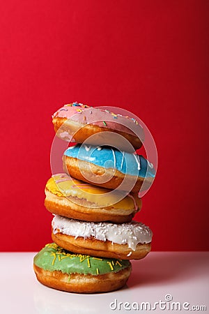 Donuts in multi-colored glaze stacked on top of each other on a red background, copy space. Bakery advertising concept Stock Photo