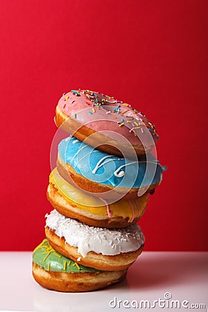 Donuts in multi-colored glaze stacked on top of each other on a red background, copy space. Bakery advertising concept Stock Photo