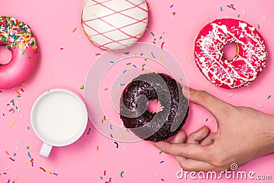 Donuts, sweetmeats candy on pink background. Hand holds donut Stock Photo