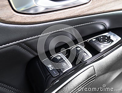 Door handle with power window control buttons of a luxury passenger car. Black perforated leather interior with stitching. Modern Stock Photo