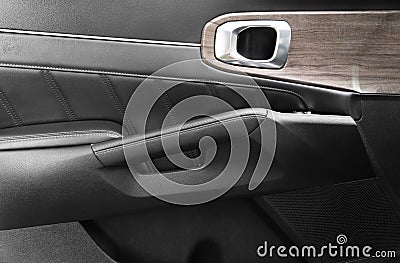 Door handle with power window control buttons of a luxury passenger car. Black perforated leather interior with stitching. Modern Stock Photo