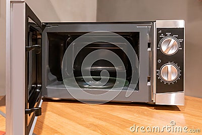 Door open microwave oven on wooden table in kitchen Stock Photo