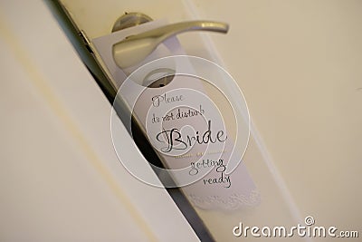 Door sign hanging on a door handle reads `Do not disturb, bride getting ready` Stock Photo