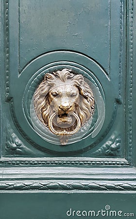 Doorknocker with head of lion on a green wooden door Stock Photo