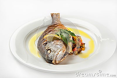 Dorada fish head close up. Grilled dorade on a white plate with sauce, arugula on a white plate isolated on whitebackground Stock Photo