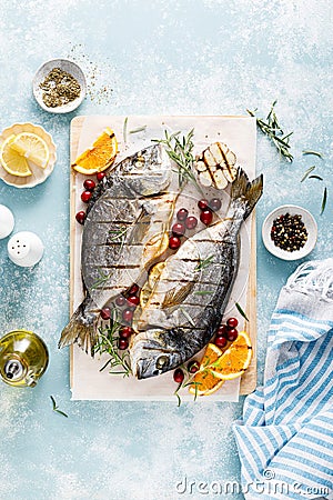 Dorado fish grilled with oranges, cranberries and rosemary, Mediterranean food. Christmas festive healthy dinner, top view Stock Photo