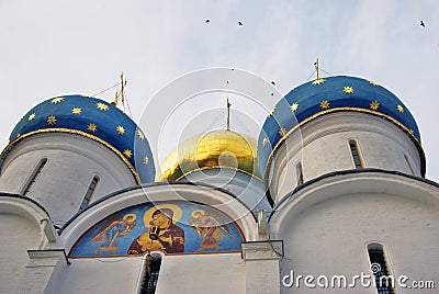 Dormition church of Trinity Sergius Lavra. Birds fly around cupolas Stock Photo