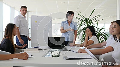 Dos personas cerca de ideas de las ofertas del flipchart cerca de hombres de negocios escuchan presentación almacen de metraje de vídeo Dos personas cerca de ideas de las ofertas del flipchart cerca de hombres de negocios escuchan presentación almacen de metraje de vídeo