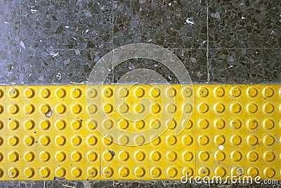 Close up yellow braille block on dark granite tile floor Stock Photo