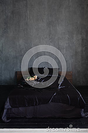 double bed with flowers in the bedroom in the dark interior room Stock Photo