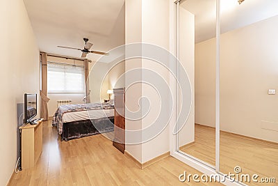 Double bedroom with white edged sliding mirrored wardrobe with large bed and wooden floorboards Stock Photo