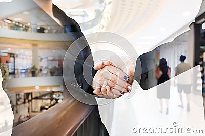 Double exposure of businesspeople shaking hands with shopping mall Stock Photo