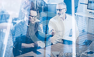 Double exposure concept.Teamwork process in modern coworking studio.Young bearded man and adult businessman making notes Stock Photo