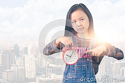 The double exposure image of the little girl point to an alarm clock and overlay with cityscape image. the concept of school, weak Stock Photo