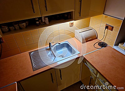 double stainless steel sink in the horseshoe-shaped kitchen. yellow painted Stock Photo