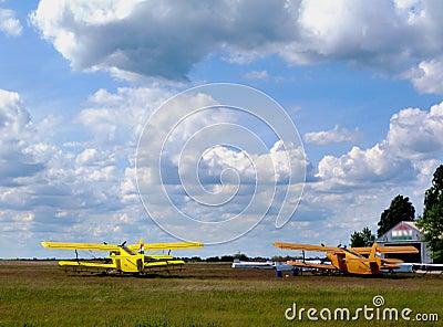 Double winged yellow airplanes in rural air field. blue sky and white clouds. Editorial Stock Photo