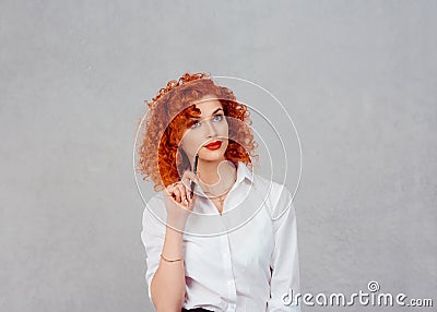 Doubtful business woman thinking pen on cheek. Red head curly ginger hair lady thoughtful girl in white formal shirt isolated on Stock Photo