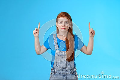 Doubtful concerned unsure redhead female making important decision, grimacing hesitant displeased, point up promo, top Stock Photo