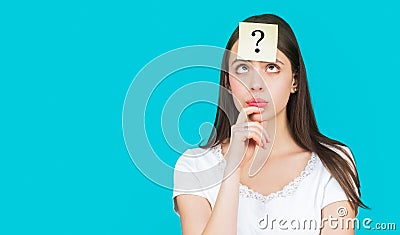 Doubtful girl asking questions to himself. Confused female thinking with question mark on sticky note on forehead. Paper Stock Photo