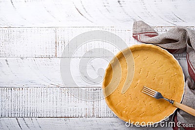 Dough for baking quiche, tart or pie in ceramic baking form ready for bake on kitchen towel over white old rustic plank wooden bac Stock Photo