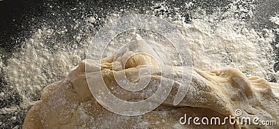 Dough kneading process. A piece of wheat dough with sprinkled flour on a black background. Side lighting. Bread making process Stock Photo