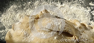 Dough kneading process. A piece of wheat dough with sprinkled flour on a black background. Side lighting. Bread making process Stock Photo